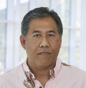 Hawaiian man, late 40s, short dark hair wearing a pink collared Hawaiian shirt